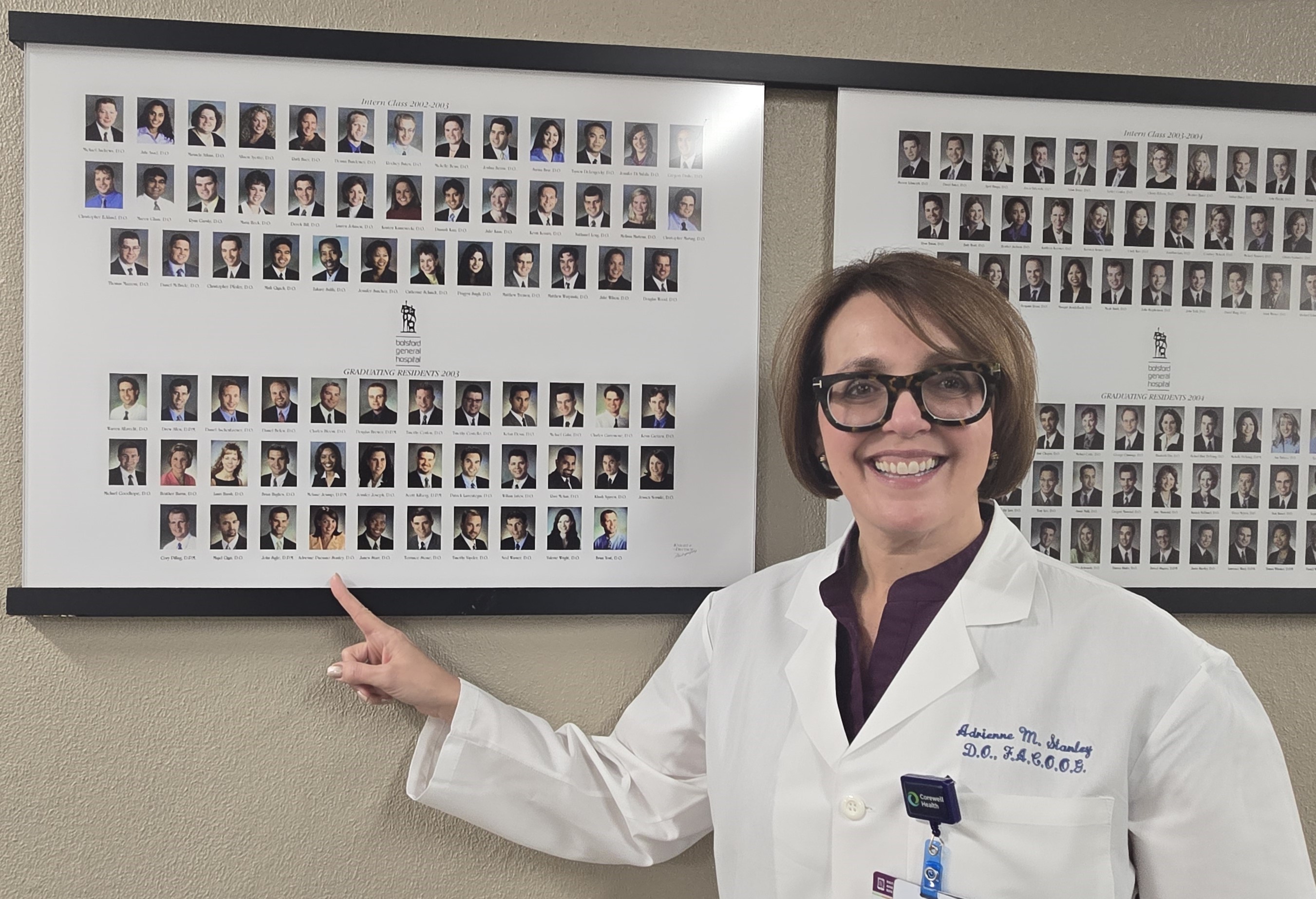 Dr. Stanley finds her picture in the 2003 resident class photo that hangs at Corewell Health Farmington Hills Hospital.